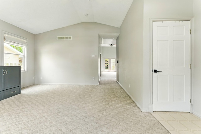 unfurnished room with vaulted ceiling, baseboards, light colored carpet, and visible vents