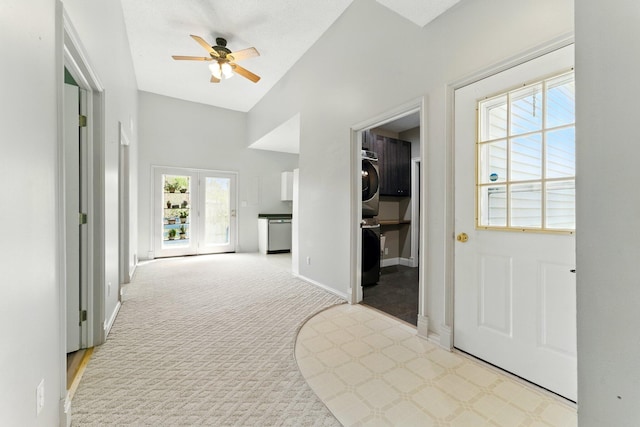 entrance foyer featuring carpet floors, baseboards, a ceiling fan, and stacked washer and dryer