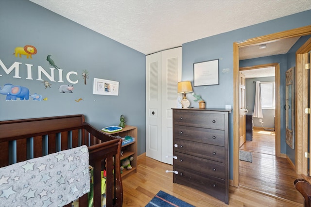 bedroom featuring a closet, baseboards, a textured ceiling, and wood finished floors