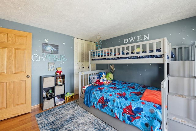 bedroom with a textured ceiling, wood finished floors, and a closet