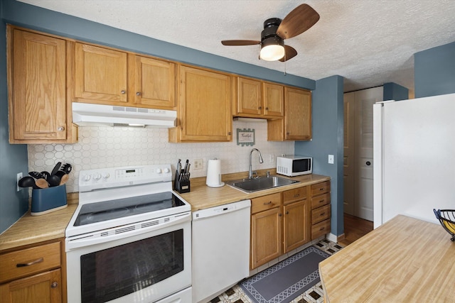 kitchen with under cabinet range hood, a sink, white appliances, and light countertops