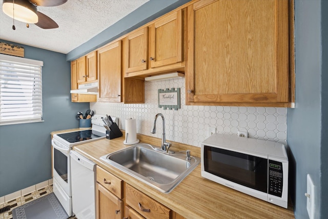 kitchen with a sink, white appliances, light countertops, decorative backsplash, and under cabinet range hood