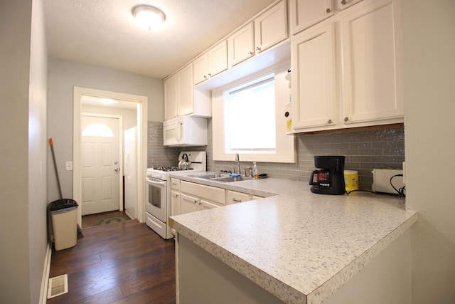 kitchen with visible vents, tasteful backsplash, a sink, white appliances, and white cabinetry