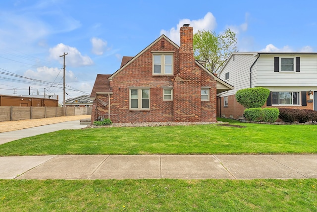 exterior space with brick siding, a lawn, fence, and a chimney