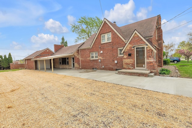 back of property with brick siding, a shingled roof, and a chimney