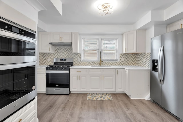 kitchen featuring a sink, light countertops, stainless steel appliances, tasteful backsplash, and under cabinet range hood