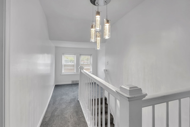 hall with dark carpet, baseboards, an upstairs landing, lofted ceiling, and visible vents