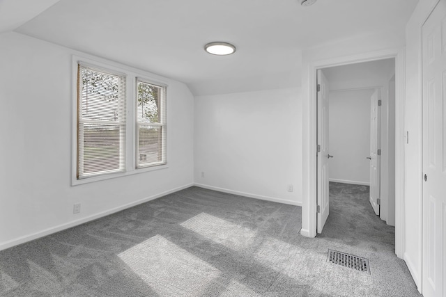 unfurnished bedroom with visible vents, carpet flooring, baseboards, and vaulted ceiling
