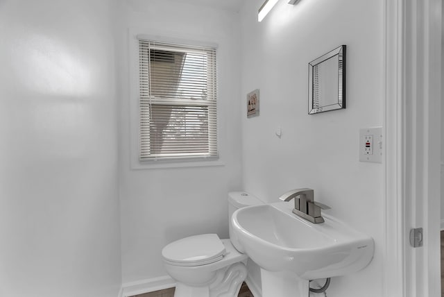 bathroom featuring baseboards, a sink, and toilet