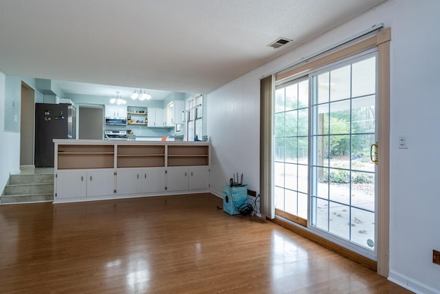 living room with visible vents, baseboards, wood finished floors, and a chandelier