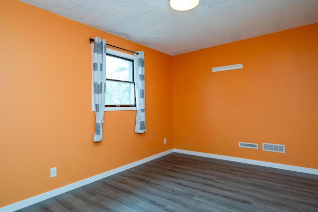 spare room featuring baseboards, visible vents, and wood finished floors