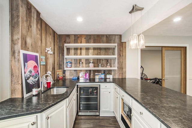 bar with dark wood finished floors, a sink, stainless steel microwave, indoor wet bar, and beverage cooler