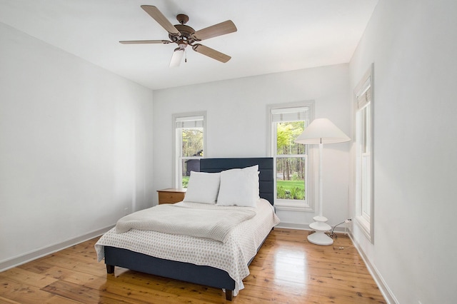 bedroom with baseboards, ceiling fan, and light wood-type flooring