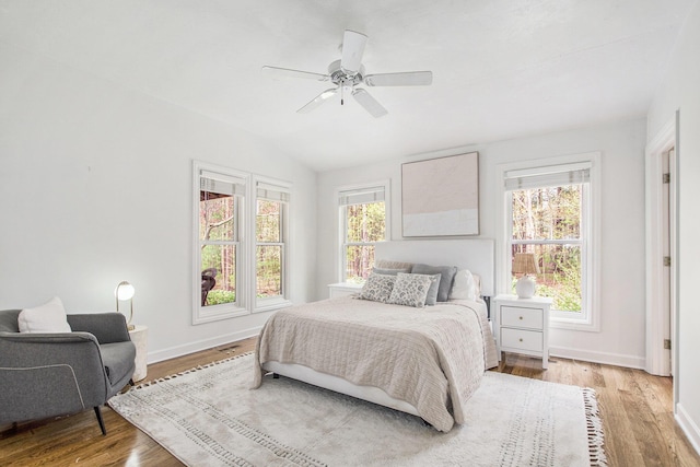 bedroom featuring multiple windows, light wood finished floors, and lofted ceiling
