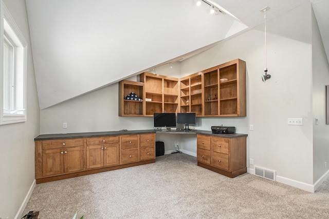 unfurnished office with track lighting, visible vents, light carpet, baseboards, and built in desk