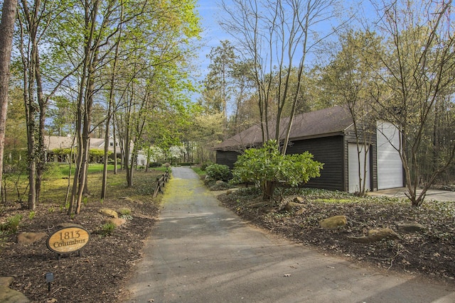view of side of property featuring concrete driveway and roof with shingles