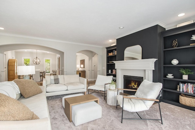 carpeted living room with arched walkways, built in shelves, recessed lighting, a lit fireplace, and ornamental molding