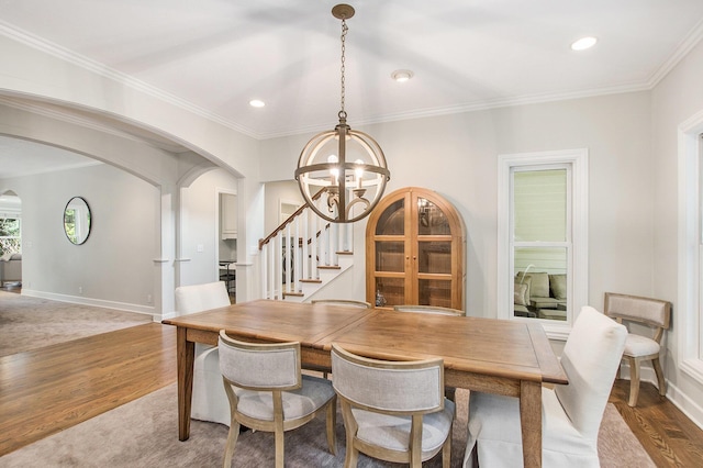 dining area with stairs, arched walkways, a chandelier, and wood finished floors