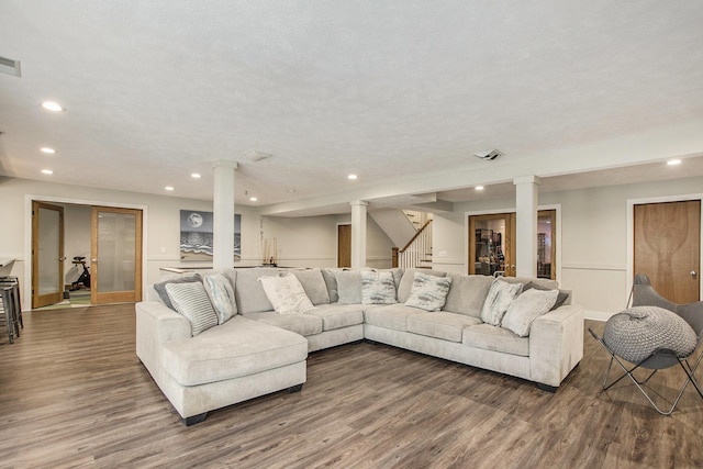 living area featuring decorative columns, recessed lighting, stairs, and dark wood-type flooring
