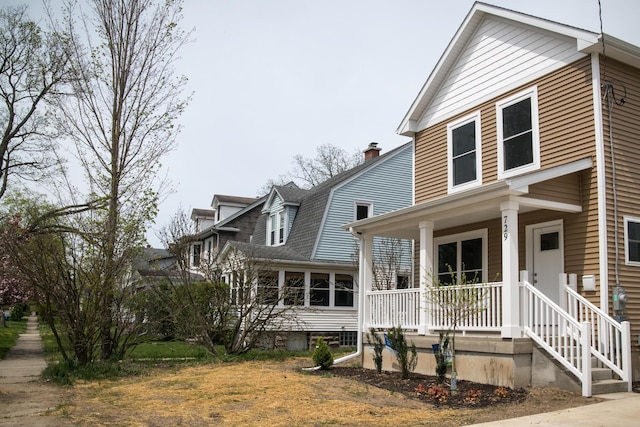 view of front of home featuring a porch, a chimney, and roof with shingles