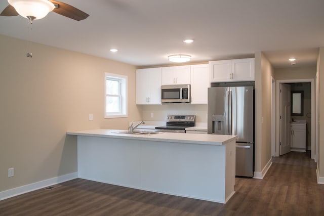 kitchen featuring a sink, light countertops, stainless steel appliances, a peninsula, and dark wood-type flooring