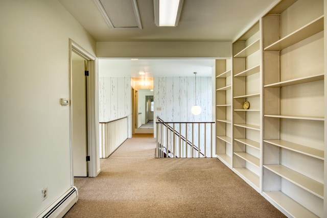 hall with attic access, a baseboard heating unit, carpet, and an upstairs landing