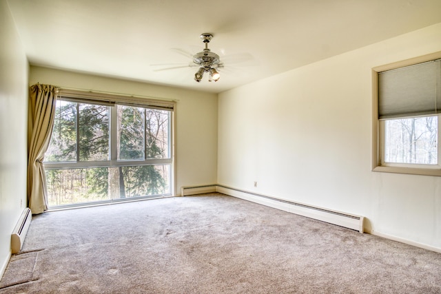 spare room with carpet flooring, ceiling fan, a baseboard heating unit, and a wealth of natural light