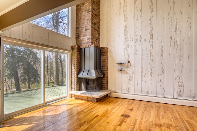 interior space with wood walls, a baseboard radiator, and hardwood / wood-style floors