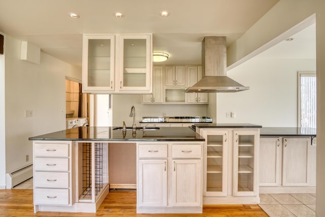 kitchen featuring dark countertops, a sink, a baseboard heating unit, and extractor fan
