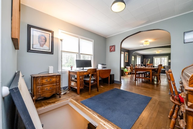 home office with crown molding, arched walkways, and hardwood / wood-style floors