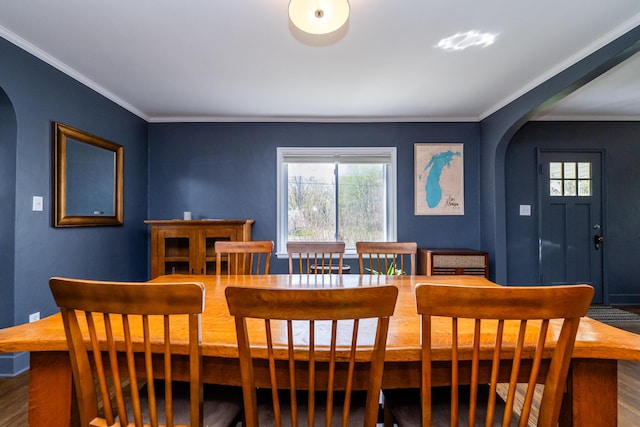 dining room featuring arched walkways, plenty of natural light, and ornamental molding
