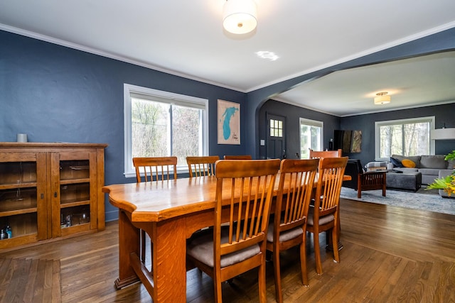 dining space featuring arched walkways, dark wood-style floors, and ornamental molding