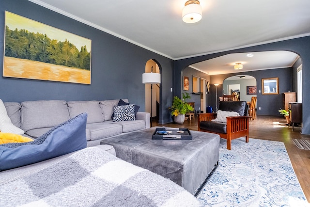 living room with crown molding, arched walkways, and wood finished floors