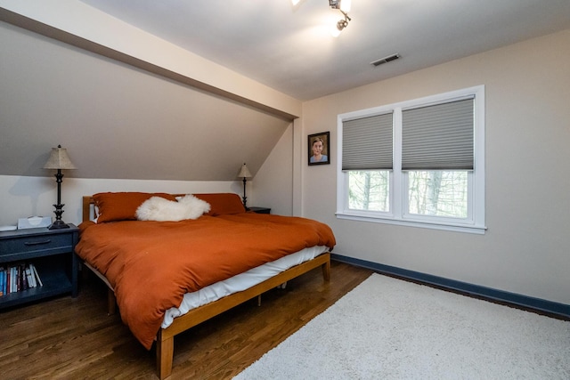 bedroom with baseboards, vaulted ceiling, wood finished floors, and visible vents