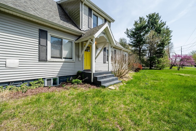 doorway to property featuring a shingled roof and a yard