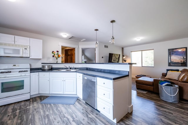 kitchen with dark countertops, a sink, a peninsula, open floor plan, and white appliances