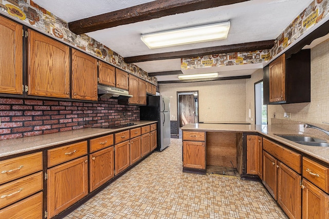10145 W Kl Ave, Kalamazoo, MI 49009 - kitchen with beam ceiling, a sink, black electric cooktop, brown cabinetry, and under cabinet range hood