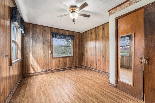 10145 W Kl Ave, Kalamazoo, MI 49009 - spare room featuring wood finished floors, baseboards, wooden walls, a textured ceiling, and a ceiling fan