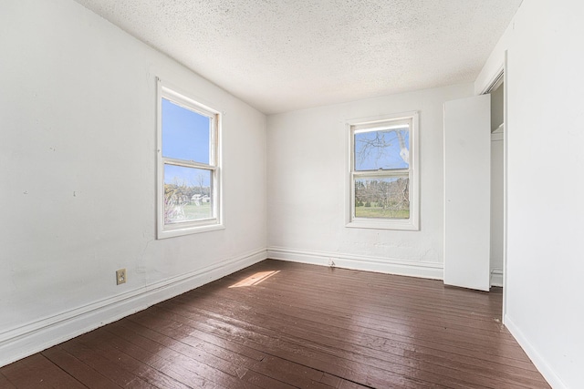 10145 W Kl Ave, Kalamazoo, MI 49009 - unfurnished bedroom with dark wood-type flooring, a textured ceiling, and multiple windows