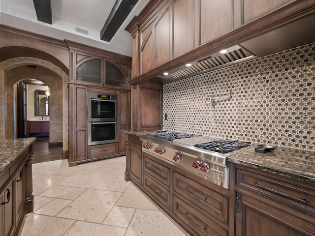 26565 Scenic, Franklin, MI 48025 - kitchen with stone tile flooring, glass insert cabinets, dark stone counters, arched walkways, and appliances with stainless steel finishes