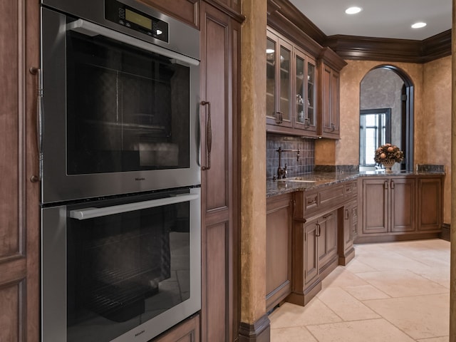 26565 Scenic, Franklin, MI 48025 - kitchen featuring stainless steel double oven, crown molding, arched walkways, glass insert cabinets, and dark stone counters