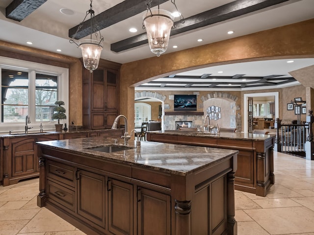 26565 Scenic, Franklin, MI 48025 - kitchen featuring stone tile flooring, a sink, arched walkways, and a center island with sink