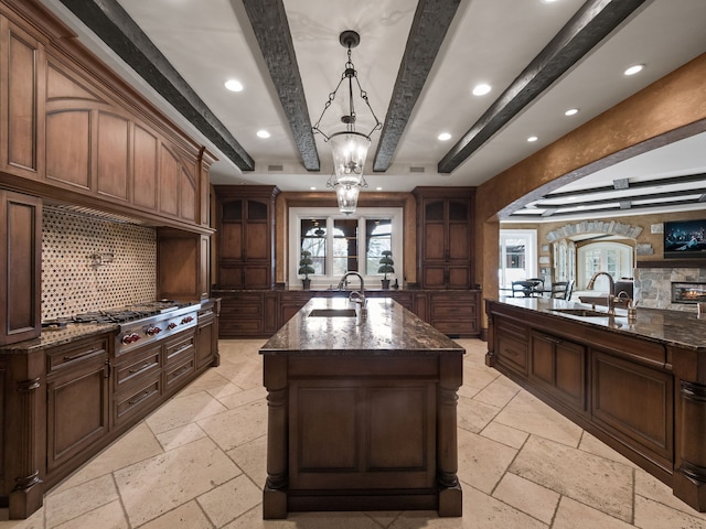 26565 Scenic, Franklin, MI 48025 - kitchen featuring a center island with sink, a sink, beamed ceiling, stone tile flooring, and stainless steel gas stovetop