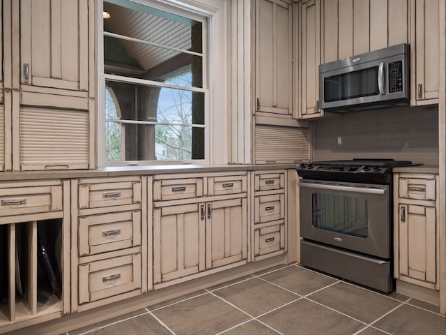 26565 Scenic, Franklin, MI 48025 - kitchen with light countertops, stainless steel appliances, decorative backsplash, cream cabinetry, and dark tile patterned flooring