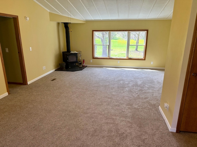 unfurnished living room with baseboards, carpet, and a wood stove