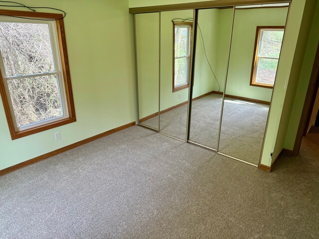 unfurnished bedroom with a closet, carpet, baseboards, and multiple windows