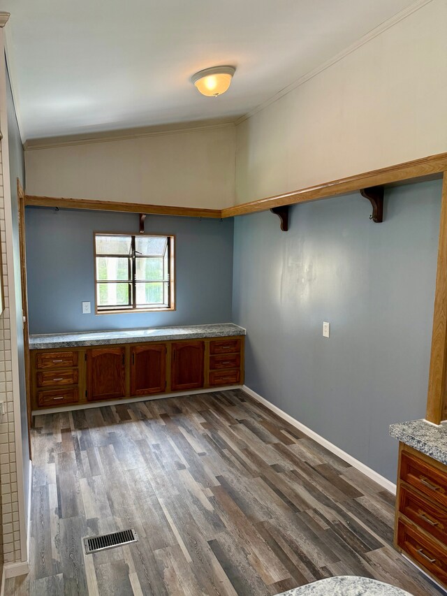 empty room with visible vents, baseboards, crown molding, and dark wood-style floors
