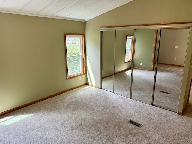 unfurnished bedroom with visible vents, carpet flooring, baseboards, and lofted ceiling