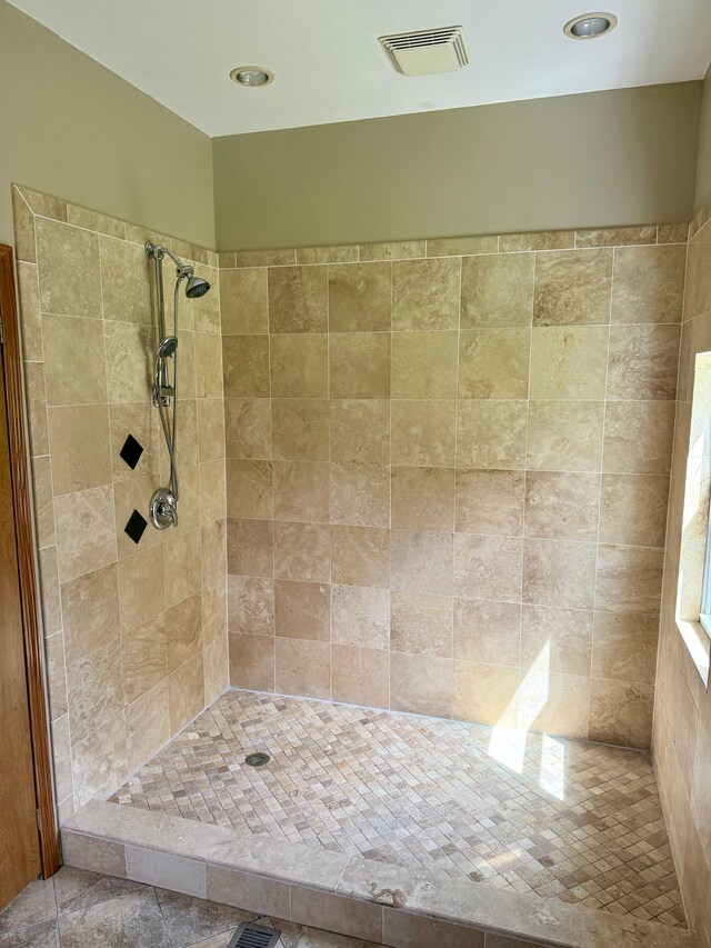 bathroom with visible vents and a tile shower