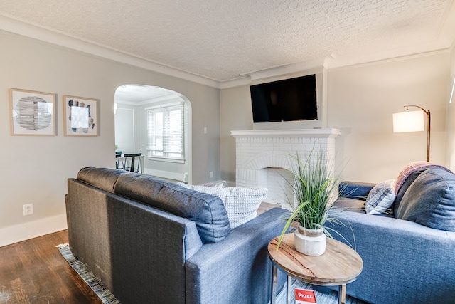 17215 Warrington Dr, Detroit, MI 48221 - living area featuring dark wood-style flooring, a textured ceiling, arched walkways, a brick fireplace, and baseboards